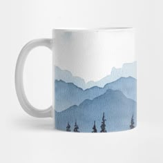 a blue and white coffee mug with mountains in the background, on a white surface