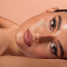 a woman with freckled hair and brown eyes laying on her stomach looking at the camera