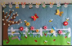 a bulletin board decorated with paper flowers, bugs, and rabbits in the grass next to a fence