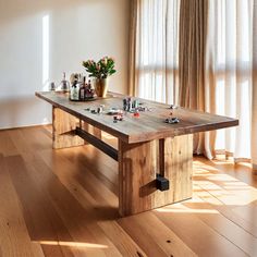 a wooden table sitting on top of a hard wood floor next to a vase filled with flowers