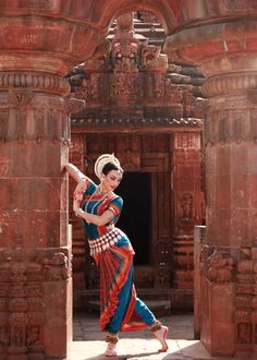 a woman is dancing in front of an old building