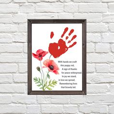 a red handprint on a white brick wall next to a frame with an image of two poppies