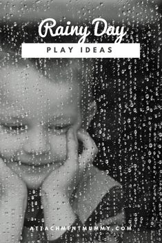 a young boy is smiling while holding his head in front of a rain covered window