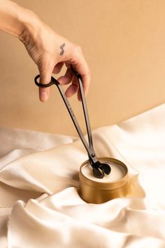 a person is holding scissors over a can