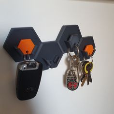 two keys are hanging on the wall with hexagonal key holders attached to it