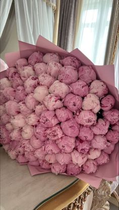 a bouquet of pink flowers sitting on top of a table in front of a mirror