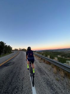 a bicyclist rides down an empty road at dusk in the country side