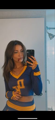 a woman taking a selfie in front of a mirror wearing a cheerleader outfit