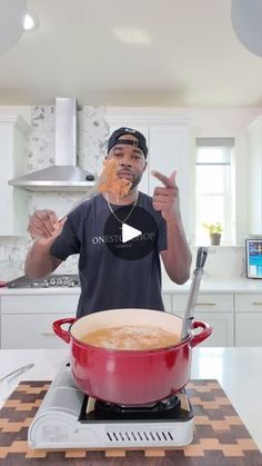 a man standing in front of a red pot on top of a stove with food covering his face