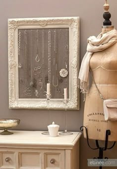 an image of a mannequin in front of a white frame with jewelry hanging on it