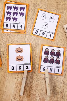 four matching cards with numbers and pictures on them for halloween themed counting practice, along with two wooden pegs