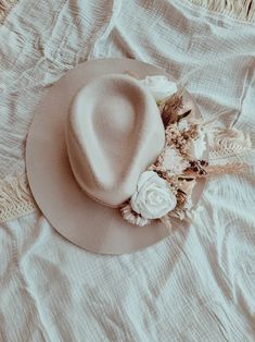 a white hat on top of a bed next to a lace and flower pillow cover