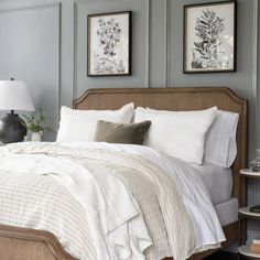 a bed with white linens and pillows in a bedroom next to two framed pictures on the wall