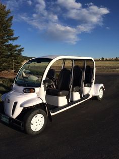 a white golf cart is parked on the side of the road with its doors open