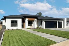 a white house with grass in front of it and two garages on the other side