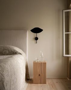 a bedroom with a bed, night stand and lamp on the wall next to it