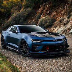 a blue chevrolet camaro is parked on the road