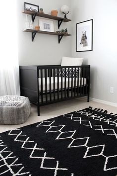 a baby's room with a black and white rug on the floor next to a crib