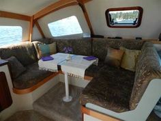 the inside of a boat with couches, tables and windows on it's side