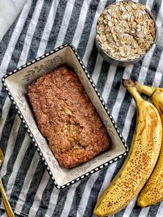 a loaf of banana bread in a bowl next to some bananas and oatmeal