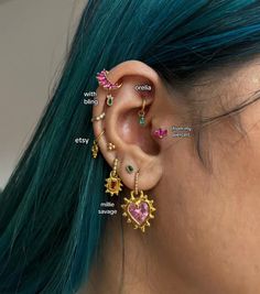 a woman with green hair wearing different colored ear piercings and colorful stones on her ears