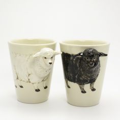 two cups with sheep painted on them, one is white and the other is black