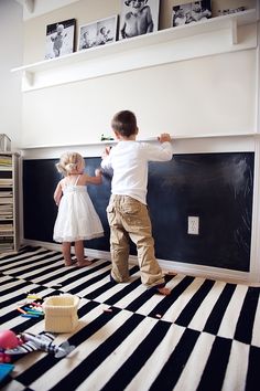 two young children are playing on the floor in their room with black and white striped carpet