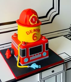 a cake made to look like a firetruck with a helmet on top and the number six written on it