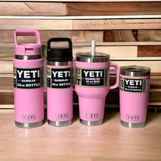 three pink yeti mugs sitting next to each other on top of a wooden table