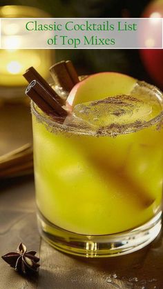 a close up of a drink in a glass with an apple and cinnamon stick on the rim