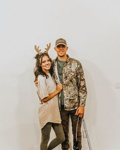 a man and woman standing next to each other in front of a wall with deer antlers on it