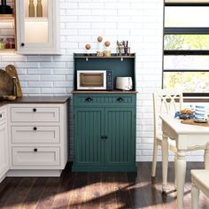 a kitchen with white and green cabinets, wood flooring and an open shelf on the wall