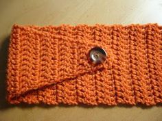 an orange crocheted cloth with a button on it