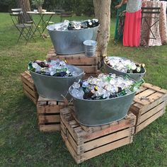 three buckets filled with beer bottles sitting on top of wooden pallets in the grass