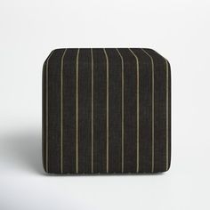 a black and brown striped ottoman cover on a white surface with an off - white wall in the background