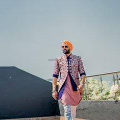 a man in an orange turban walks down the street with his hand on his hip