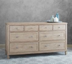 a wooden dresser sitting on top of a carpeted floor next to a gray wall