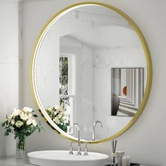 a bathroom sink with a round mirror on the wall above it and flowers in front of it