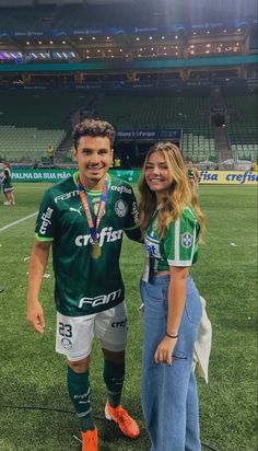 a man and woman standing next to each other on a soccer field