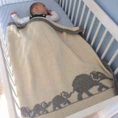 a baby laying in a crib with a blanket over it's head and an elephant design