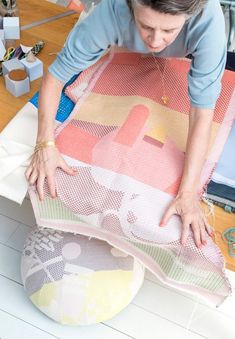 a woman is making a quilt on the floor