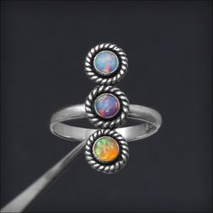 This gorgeous ring features (3) Swarovski crystals or synthetic opals in your birthstone/opal color choice! You can choose to have all one color or pick your 3 favorite! Each stone is hand set in a handmade bezel setting. The rope design has been oxidized to bring out its lovely texture, while the whole ring is polished by hand to a high shine. Handcrafted from sterling silver. • sold individually• sterling silver, Swarovski crystals, synthetic opals• stones: 4mm• bar length: ~21mm• band width: Adjustable Opal Ring Birthstone With Round Stone, Adjustable Cabochon Opal Ring For Anniversary, Nickel Free Adjustable Opal Promise Ring, Adjustable Nickel-free Opal Promise Ring, Opal Birthstone Ring With Round Stone, Opal Birthstone Ring With Accent Stones For Promise, Adjustable Opal Ring With Accent Stones For Anniversary, Adjustable Opal Crystal Ring For Anniversary, Adjustable Nickel-free Opal Ring For Anniversary