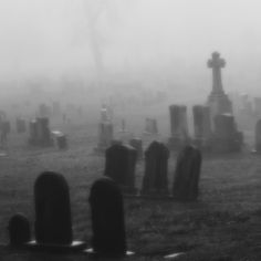 a cemetery in the fog with headstones and crosses on it's tombstones