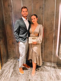 a man and woman standing next to each other in front of a wall with mirrors