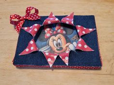 a minnie mouse photo album with red polka dots and a bow on the top, sitting on a wooden surface