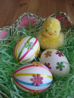 an easter basket with three decorated eggs and a yellow chick