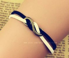 a close up of a person wearing a black and white bracelet with an intertwined knot