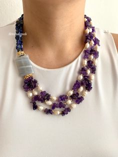 a woman wearing a purple and white beaded necklace