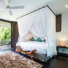 a bedroom with a white canopy bed sitting on top of a hard wood floor next to a sliding glass door