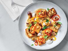 a white plate topped with tofu and veggies on top of a table